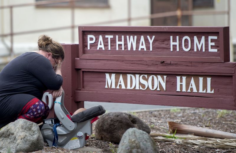 A woman, who declined to give her name, cries after placing flowers at a sign at the Veterans Home of California, the morning after a hostage situation in Yountville, Calif., on Saturday, March 10, 2018. A daylong siege at The Pathway Home ended Friday evening with the discovery of four bodies, including the gunman, identified as Albert Wong, a former Army rifleman who served a year in Afghanistan in 2011-2012. (AP Photo/Josh Edelson)