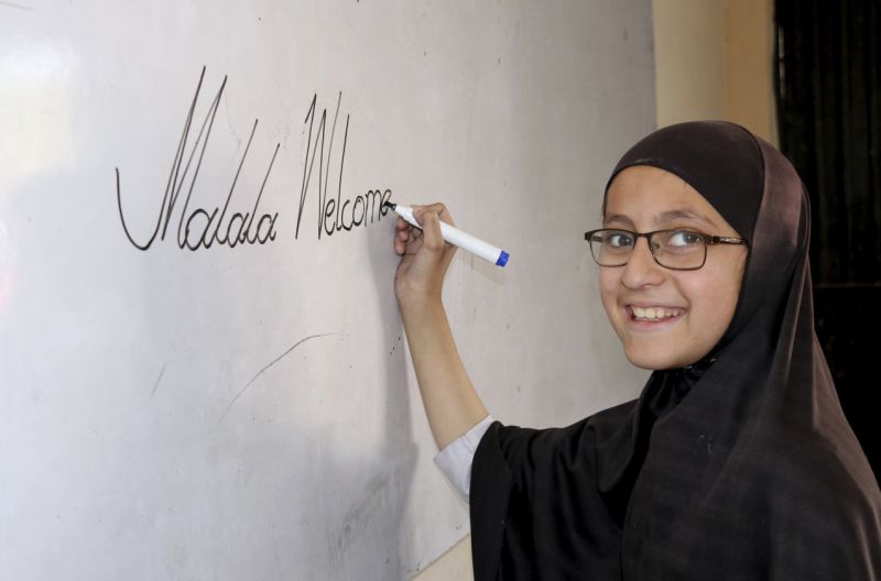 A Pakistani student of the school of Nobel Peace Prize winner Malala Yousafzai writes on a board writes on a board, in her hometown of Swat Valley in Pakistan, Friday, March 30, 2018. A Pakistani women's activist says Malala Yousafzai, who is back in Pakistan for the first time since the Taliban shot her in 2012, is hoping to visit her Swat Valley hometown but that the trip depends on security clearances from the government.(AP Photo/Naveed Ali)