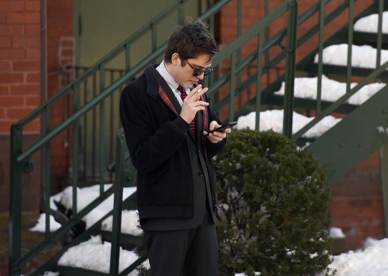 Lucian Wintrich, White House correspondent for the right-wing blog Gateway Pundit, smokes a cigarette while looking at his phone near Rockville Superior Court in Vernon, Conn., Monday, Dec. 11, 2017. Charges of breach of peace against Wintrich were dropped stemming from a Nov 28 incident at the University of Connecticut at which Wintrich delivered a speech titled