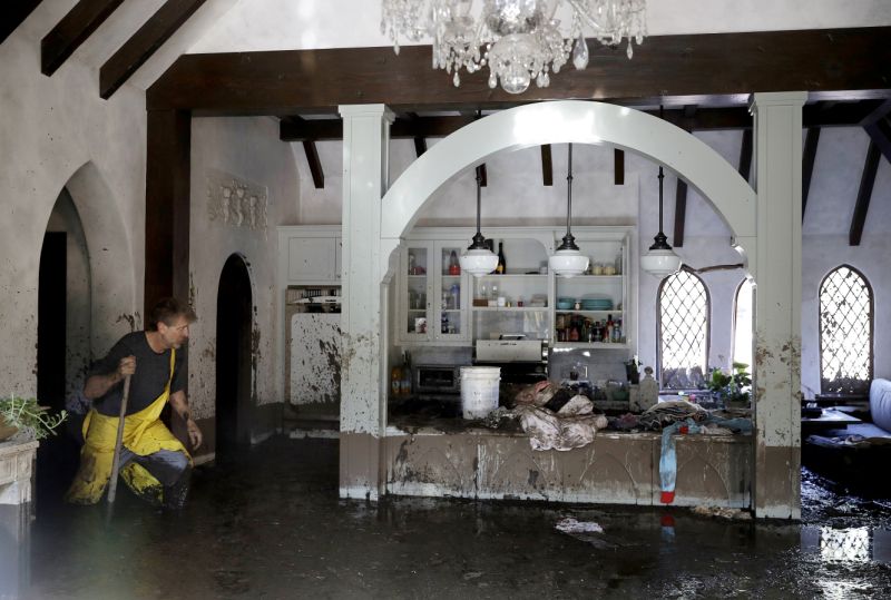 Bill Asher walks through mud in his home damaged by storms in Montecito, Calif., Thursday, Jan. 11, 2018. Rescue workers slogged through knee-deep ooze and used long poles to probe for bodies Thursday as the search dragged on for victims of the mudslides that slammed this wealthy coastal town. (AP Photo/Marcio Jose Sanchez)