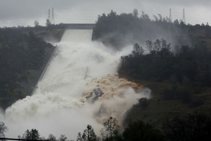 FILE - In this Feb. 9, 2017 file photo, water flows through a break in the wall of the Oroville Dam spillway in Oroville, Calif. One year after the closest thing to disaster at a major U.S. dam in a generation, federal dam regulators say they are looking hard at how they overlooked the built-in weaknesses of old dams like California's Oroville Dam for decades, and expect dam managers around the country to study their old dams and organizations equally hard. (AP Photo/Rich Pedroncelli, file)