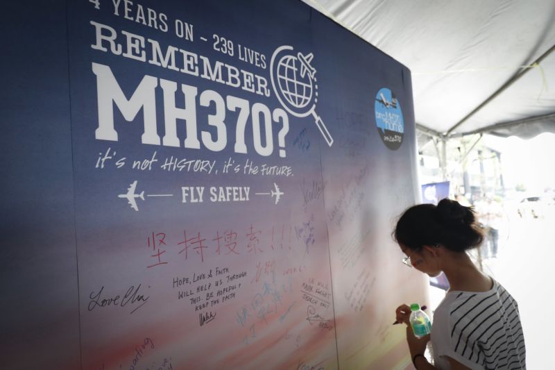 A girl writes a condolence message during the Day of Remembrance for MH370 event in Kuala Lumpur, Malaysia, Saturday, March 3, 2018. The remembrance event marked the fourth anniversary of the jet's March 8, 2014, disappearance. (AP Photo/Vincent Thian)