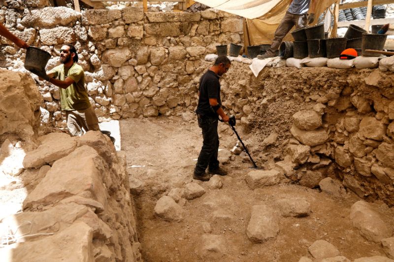 An Israeli archeologist scans the ground with a metal detector at an excavation site beneath the old city walls of Jerusalem; Jerusalem's Old City remains on the UNESCO endangered sites list but wording which Israel considered aggressive has been removed