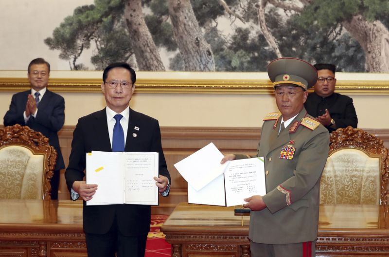 FILE - In this Sept. 19, 2018, file photo, South Korea's Defense Minister Song Young-moo, front left, and North Korea's Minister of the People's Armed Forces No Kwang Chol, front right, hold the documents after signing as South Korean President Moon Jae-in, rear left, and North Korean leader Kim Jong Un, rear right, clap at the Paekhwawon State Guesthouse in Pyongyang, North Korea. North and South Korea began removing mines at two sites inside their heavily fortified border Monday, Oct. 1,  as part of their recent deals to ease decades-long military tensions.(Pyongyang Press Corps Pool via AP, File)