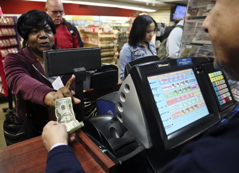 Annette Gray, left, from Valley Stream, N.Y., buys lottery tickets Friday Oct. 19, 2018, in New York. The estimated jackpot for Friday's Mega Millions drawing has soared to $1 billion. Gray said it's about 
