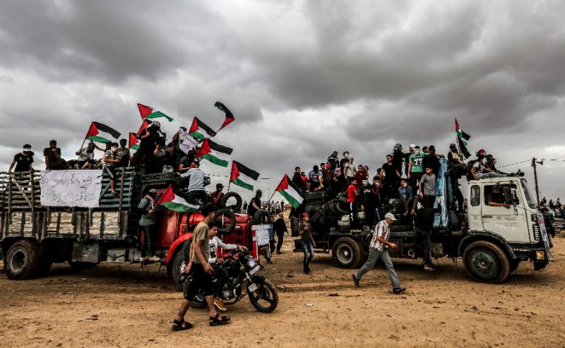 Palestinian protesters ride in trucks waving Palestinian flags as they bring tyres to be burnt for cover during clashes along the border with Israel east of Gaza City (AFP Photo/MAHMUD HAMS)