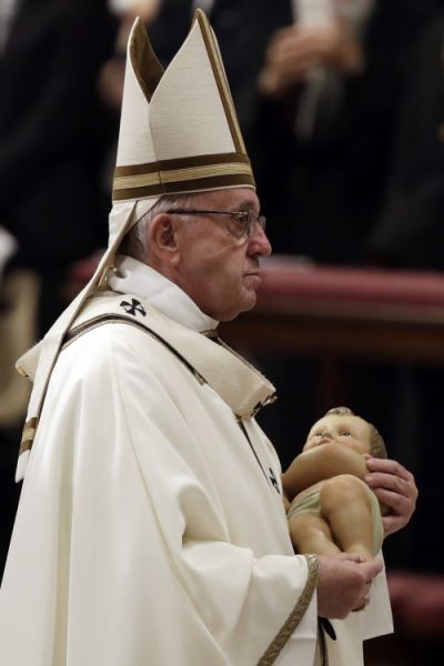 Pope Francis holds a statue of baby Jesus as he leaves at the end of the Christmas Eve Mass in St. Peter's Basilica at the Vatican, Monday, Dec. 24, 2018. (AP Photo/Alessandra Tarantino)