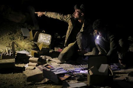 A fighter of Syrian Democratic Forces (SDF) gestures as he sits near ammunition in the village of Baghouz, Deir Al Zor province, Syria March 11, 2019. REUTERS/Rodi Said