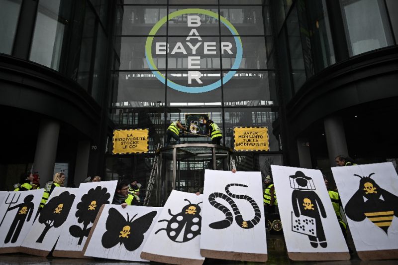 (FILES) In this file photo taken on March 14, 2019, activists stage a flash protest organised by the international movement Attac at the offices of Bayer - which recently acquired Monsanto - in La Garenne Colombes near the financial district of La Defense on the outskirts of Paris.Germany's Bayer apologised on May 12, 2019 after revelations in France that its subsidiary Monsanto had a PR agency collate lists of politicians, scientists and journalists and their views on pesticides and GM crops