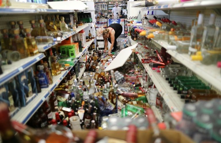 An employee cleans up toppled bottles in a convenience store on July 6, 2019 following a 7.1-magnitude earthquake in Ridgecrest, California (AFP Photo/MARIO TAMA)