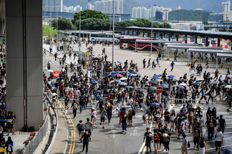 Protesters run from police at the bus terminal at Hong Kong's airport (AFP Photo/Lillian SUWANRUMPHA)