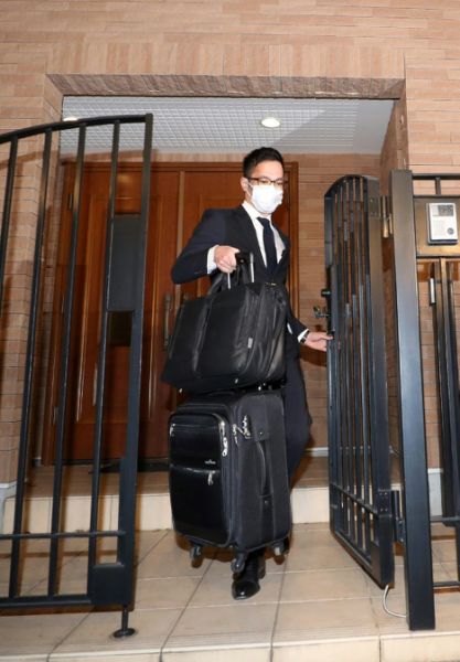 A Japanese prosecutor carries bags from the Tokyo residence of former auto tycoon Carlos Ghosn after Ghosn fled Japan to avoid a trial (AFP Photo/STR)