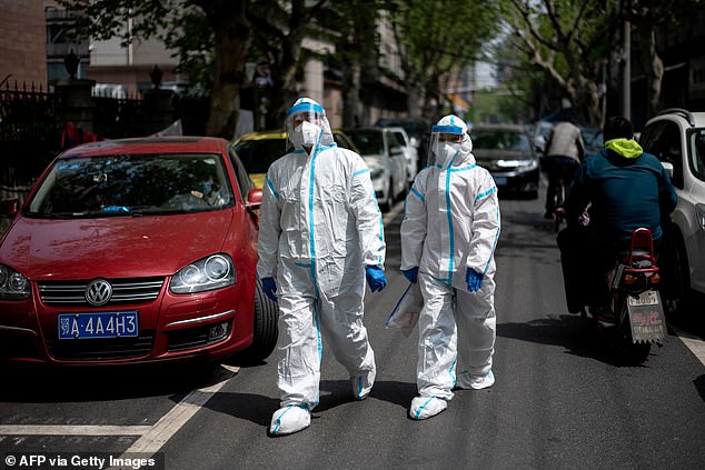 People wearing hazmat suits walking along a street today in Wuhan, China's central Hubei province where the coronavirus outbreak began