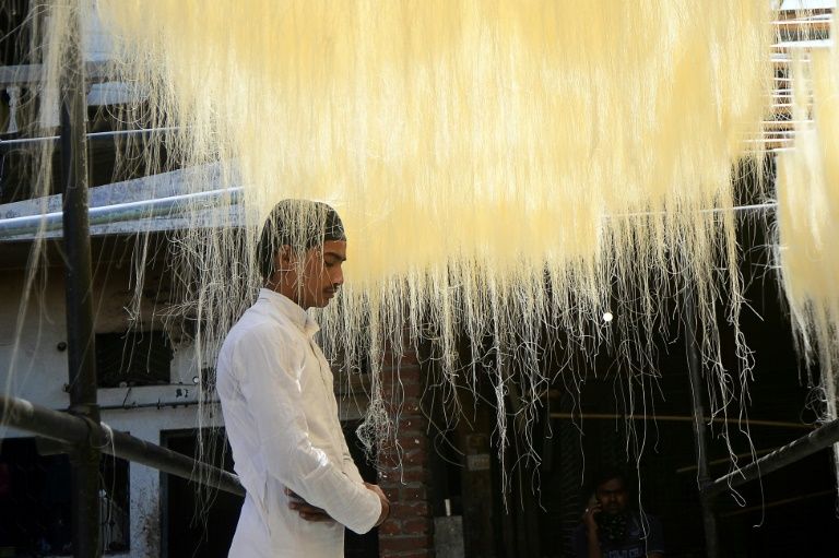 A man prays under vermicelli used to make Ramadan sweets at a factory in Allahabad in India (AFP Photo/SANJAY KANOJIA)