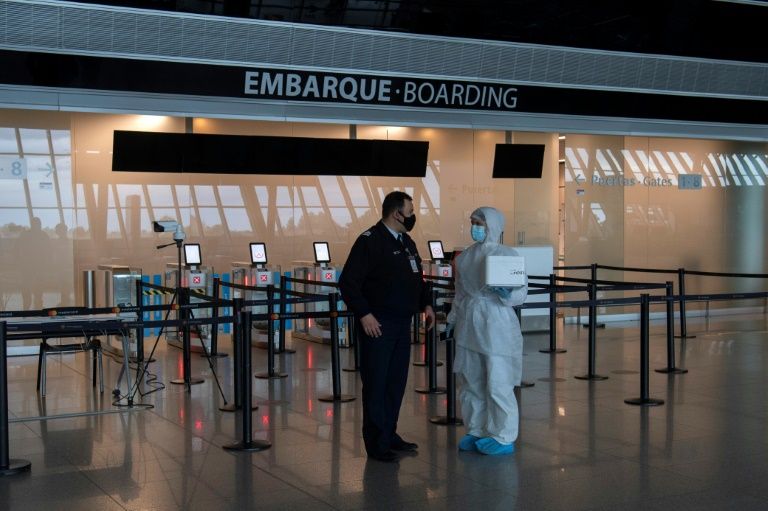 A health worker carries swabs taken from passengers of an Iberia flight to be tested on arrival at Carrasco International Airport, Uruguay (AFP Photo/Pablo PORCIUNCULA)