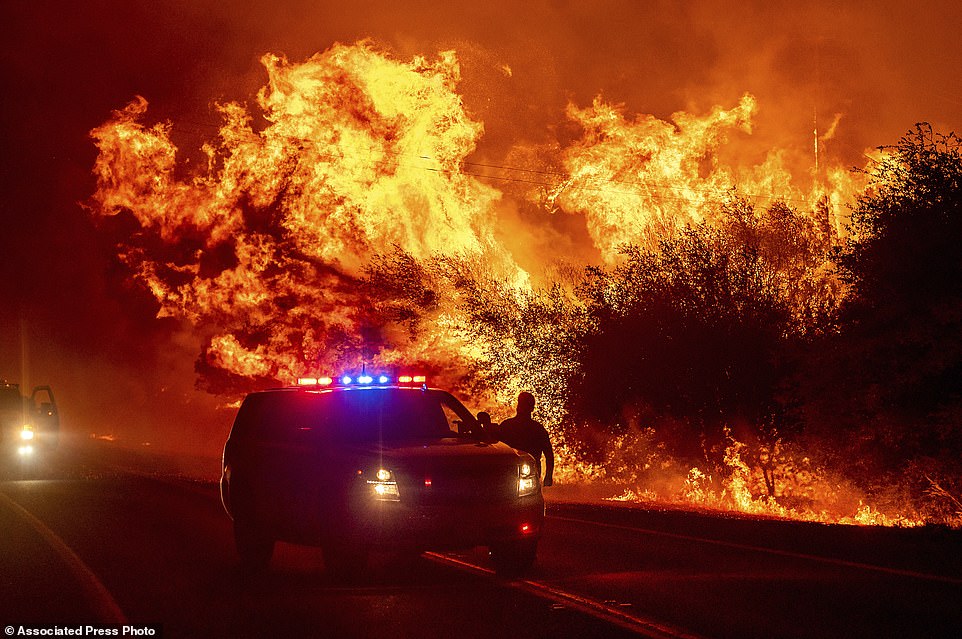 Flames lick above vehicles on Highway 162 as the Bear Fire burns in Oroville, California, Wednesday night. The blaze, part of the lightning-sparked North Complex, expanded at a critical rate of spread as winds buffeted the region