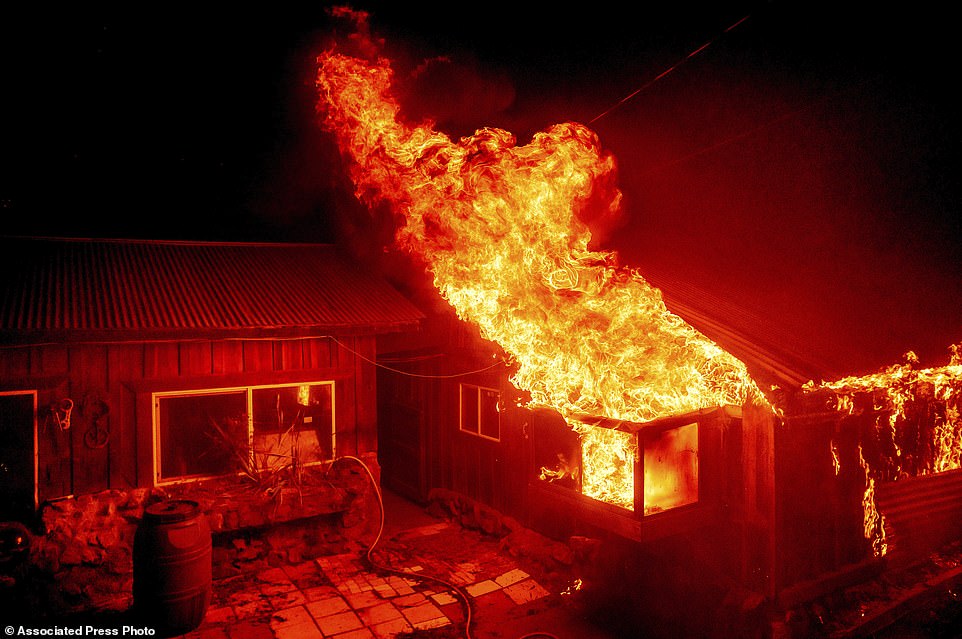Flames shoot from a window as the Bear Fire burns through the Berry Creek area of Butte County, California, in Wednesday