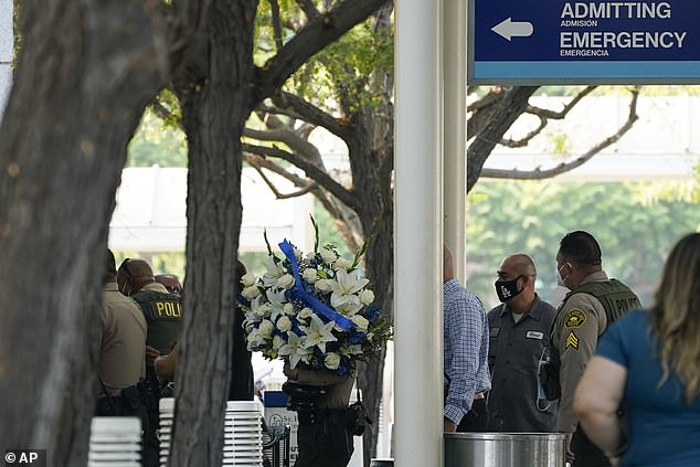 Police officers enter St. Francis Medical Center carrying flowers on Monday