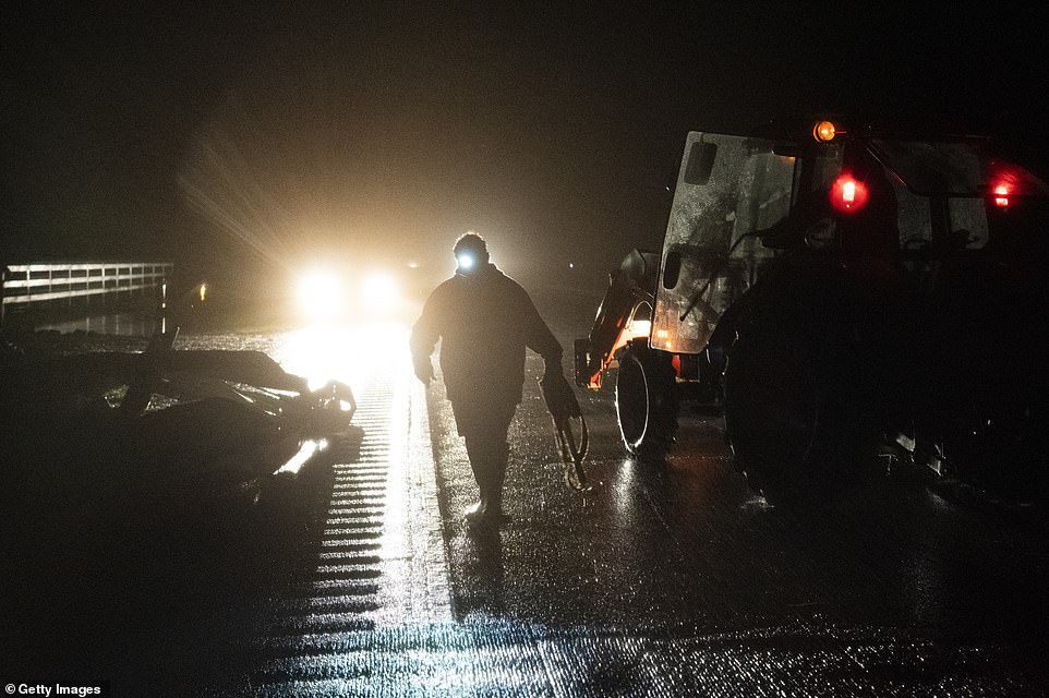 A person carries a tow cable to remove large debris using a forklift after Hurricane Delta passed through Lake Arthur overnight