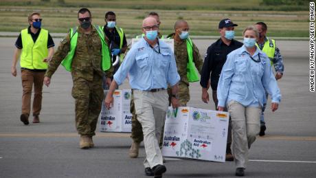 Australian officials carry boxes containing some 8,000 initial doses of the AstraZeneca vaccine at the Port Moresby international airport on March 23.