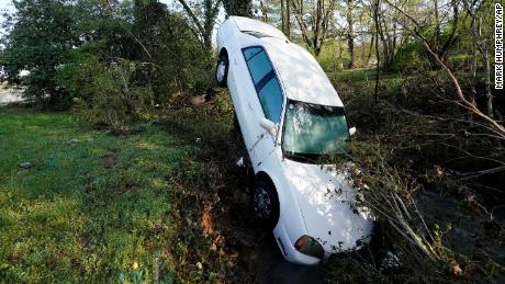 A car that was carried by floodwaters leans against a tree in a creek Sunday, March 28, 2021, in Nashville.