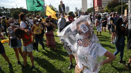 A protester wears a sign accusing Bolsonaro of genocide.