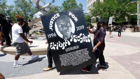 In this June 27, 2020, file photo, demonstrators carry a giant placard during a rally and march over the death of Elijah McClain outside the police department in Aurora, Colorado.
