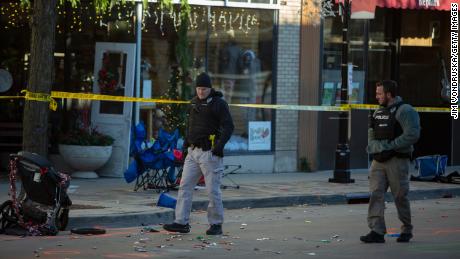 Police canvas debris left following a driver plowing into the Christmas parade on November 22, 2021, in Waukesha, Wisconsin.