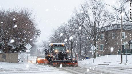 An Iowa City snow plow driver scrapes up slush along Dodge Street as snow falls during a winter storm warning, on January 14, 2022, in Iowa City, Iowa.