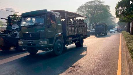 A convoy of military trucks with soldiers drives past armored personnel carriers deployed outside the Central Bank building in Yangon, Myanmar on February 15, 2021.