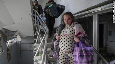 Another injured pregnant woman walks down the stairs of the damaged maternity hospital on Wednesday.