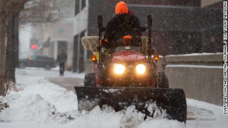 Eric Smith uses a plow on a tractor to remove snow in downtown Topeka, Kansas, on Thursday.