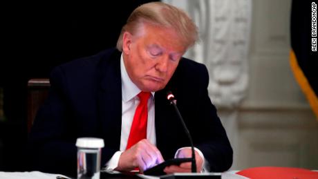 Former President Donald Trump looks at his phone during a roundtable with governors on the reopening of America's small businesses, in the State Dining Room of the White House in Washington, June 18, 2020.