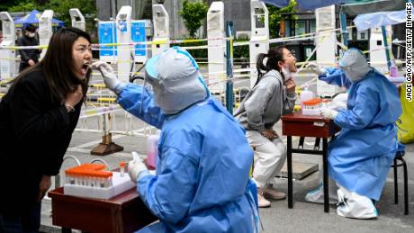 Health workers take swab samples to be tested for Covid-19 at a makeshift testing site along a street in Beijing on May 11, 2022.