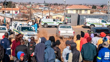People gather at the scene of an overnight bar shooting in Soweto, South Africa, Sunday July 10, 2022.