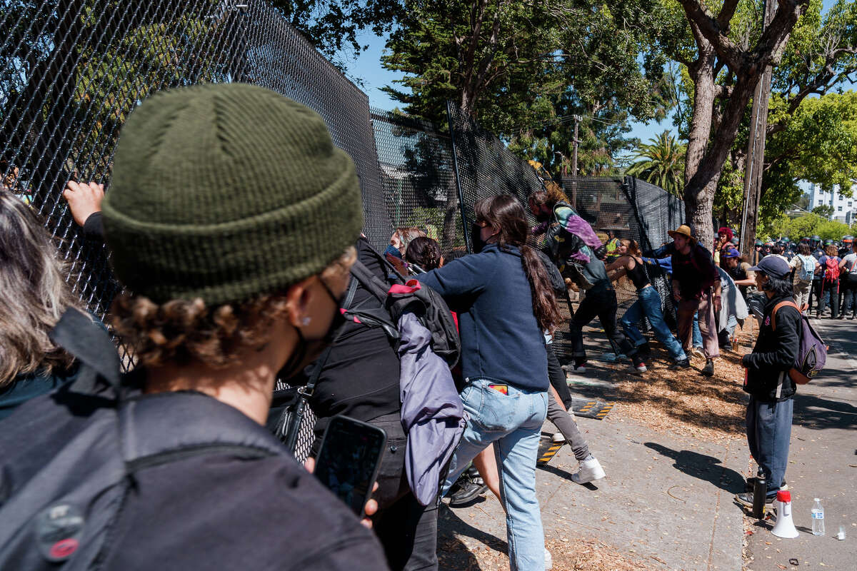 Protesters try to push down a fence at People's Park in Berkeley, Calif., on Wednesday, Aug. 3, 2022.