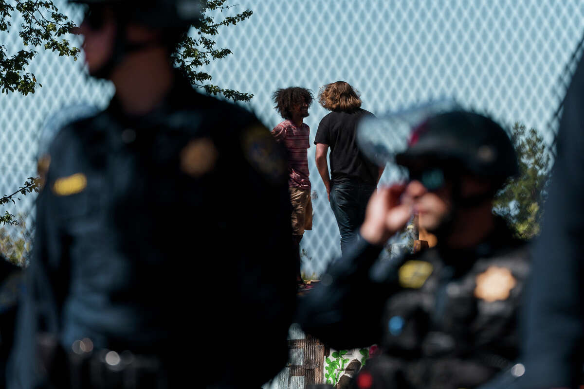 Protesters talk with one another as California Highway Patrol officers police a protest at People's Park in Berkeley, Calif., on Wednesday, Aug. 3, 2022.