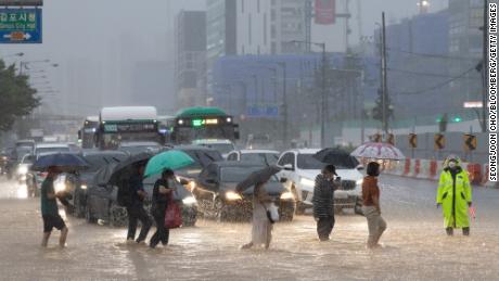 Pedestrians cross a flooded road in Gimpo, Seoul, on August 9.