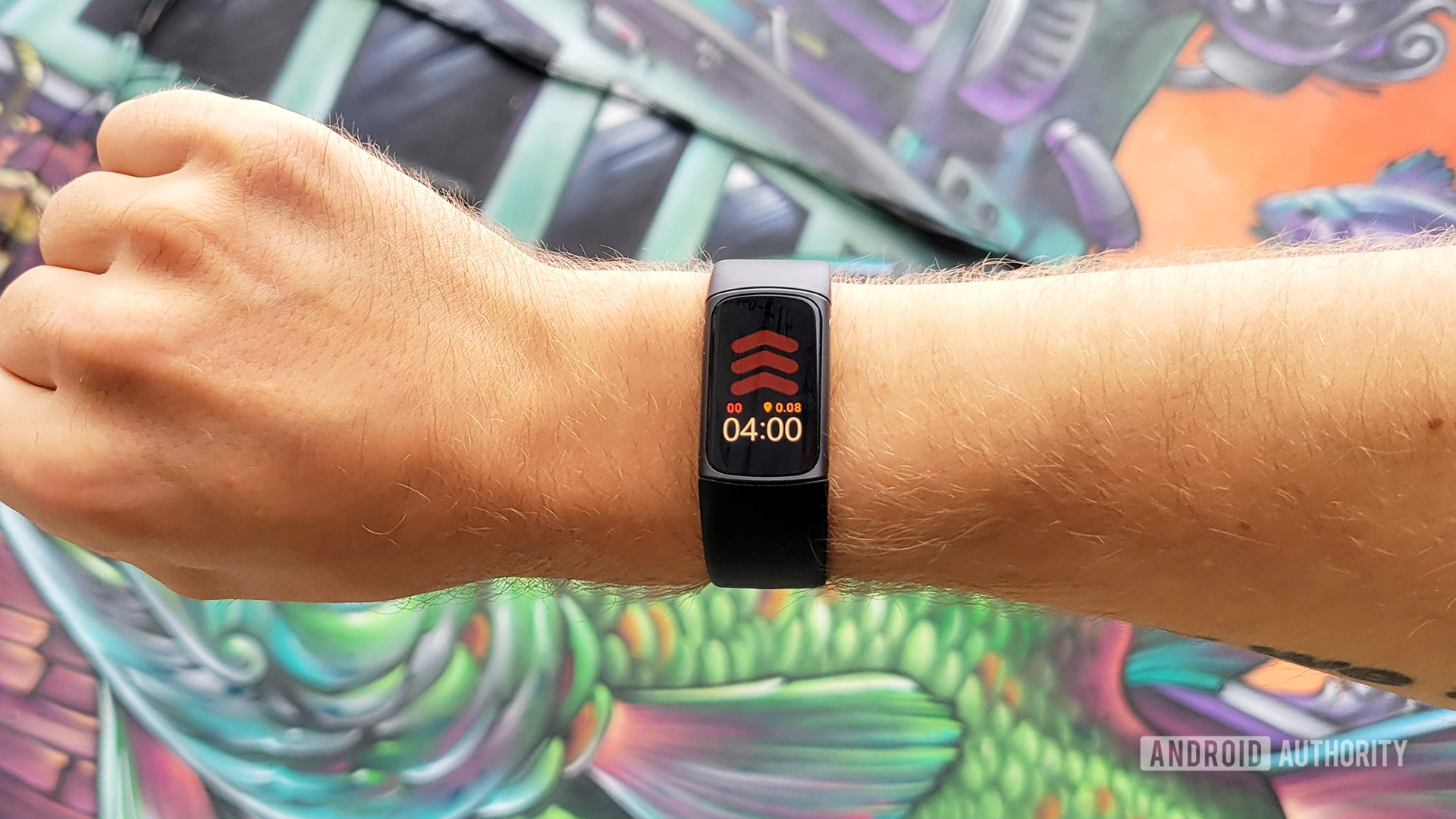 Fitbit Charge 5 Review Hero Color A user models the Fitbit Charge 5 in front of a painted mural wall.