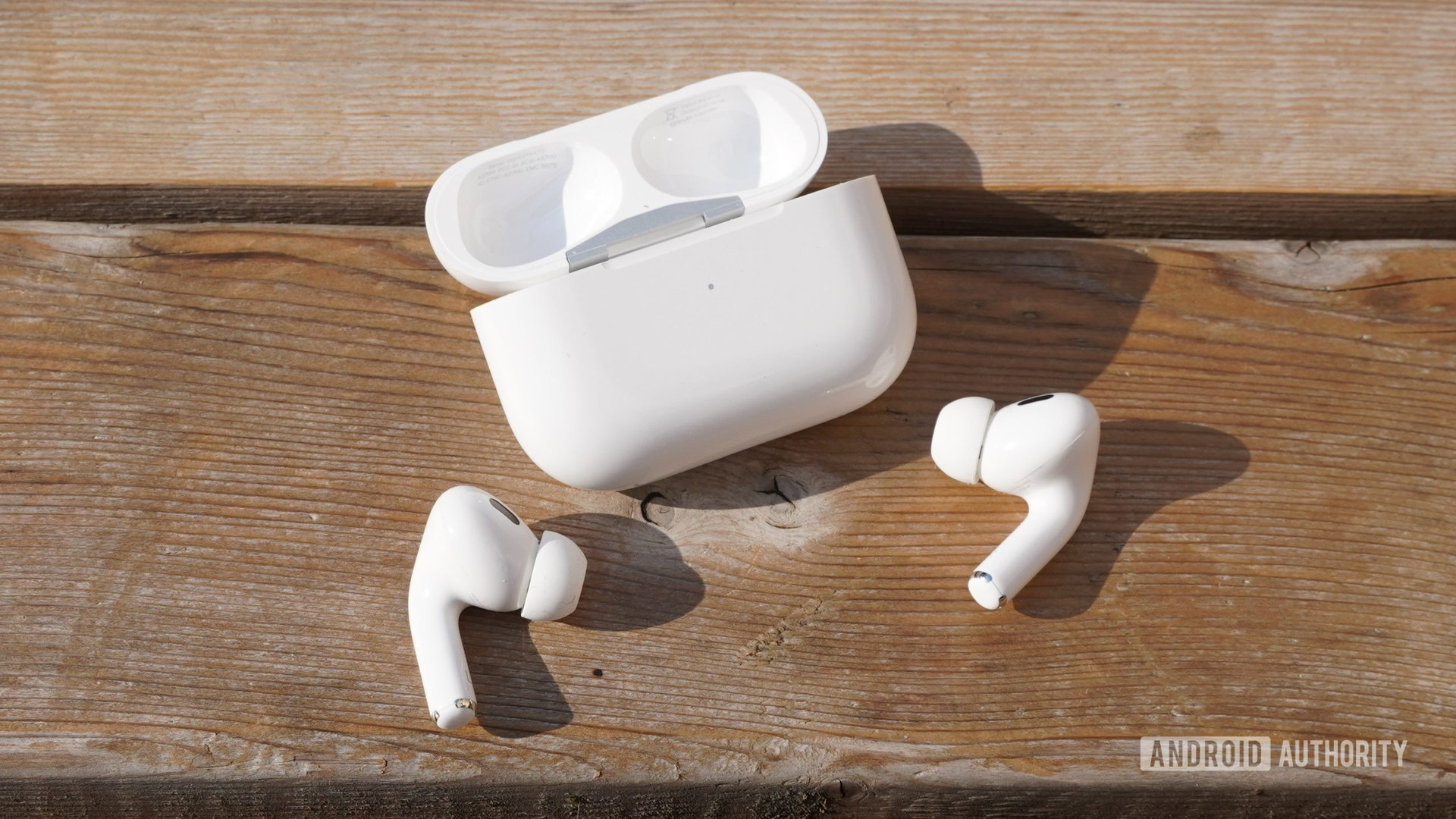 airpods pro 2 both outside case.JPG The AirPods Pro 2 sitting outside their case on a wooden surface with the case nearby.