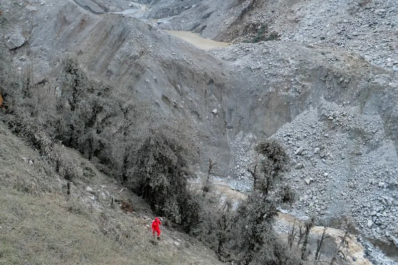 Chinese rescue worker walks near a barrier lake formed following a mudslide, seen from Gyirong county