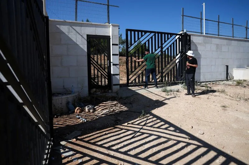 Ahmed Ridi closes the gate of his uncle Loui Ridi's house, which has been encircled by militant settlers for the past week, in Qusra
