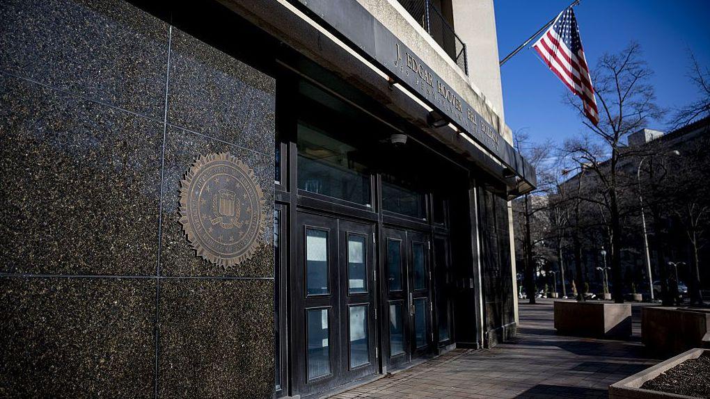 Close-up of the entrance of the FBI headquarters, with the US flag flying above it, in Washington DC