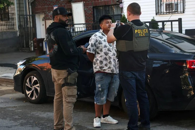 U.S. Immigration and Customs Enforcement (ICE) agents take a photograph of a man as part of a Targeted Enforcement Operation in the Corona neighborhood of the Queens borough of New York City