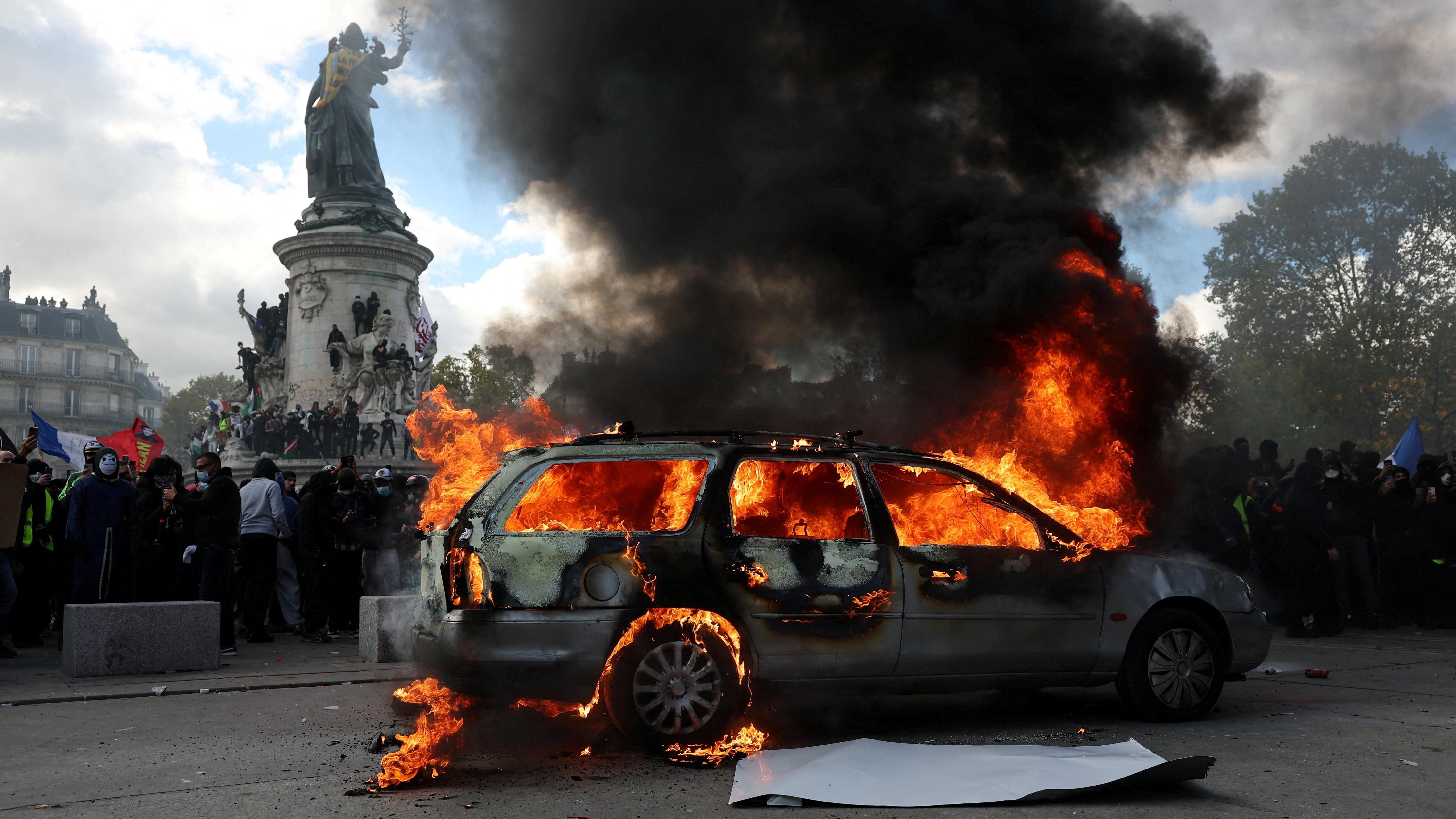 A car burns amid clashes between protesters and the French police during a demonstration against the cost of living and rising fuel prices at the Place de la Republique in Paris