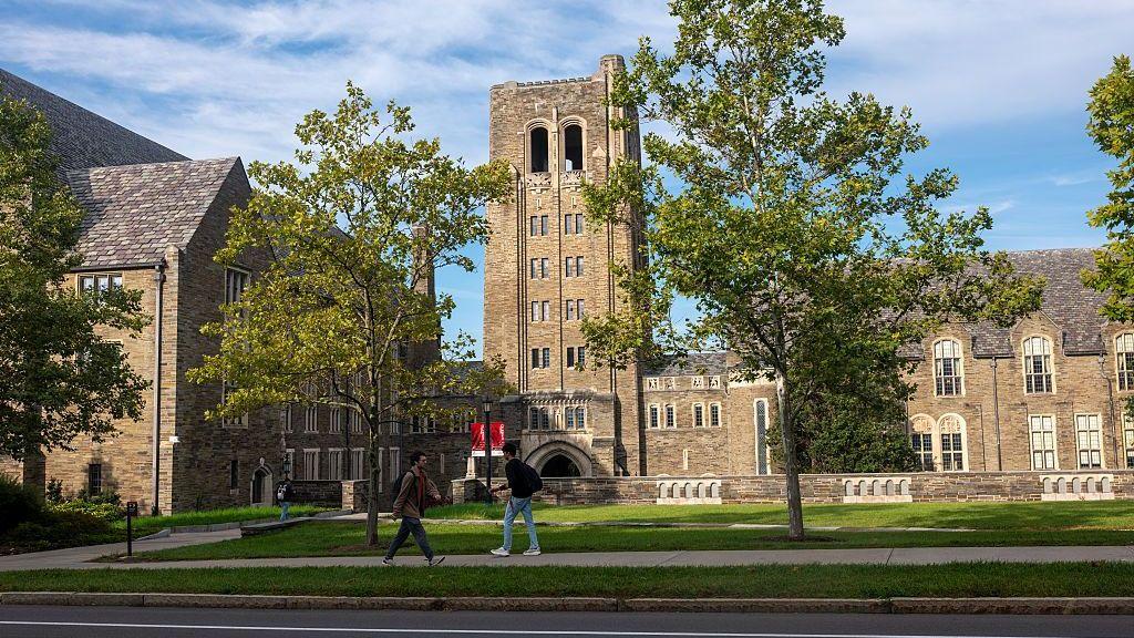 A stone building on the Cornell campus as students walk nearby