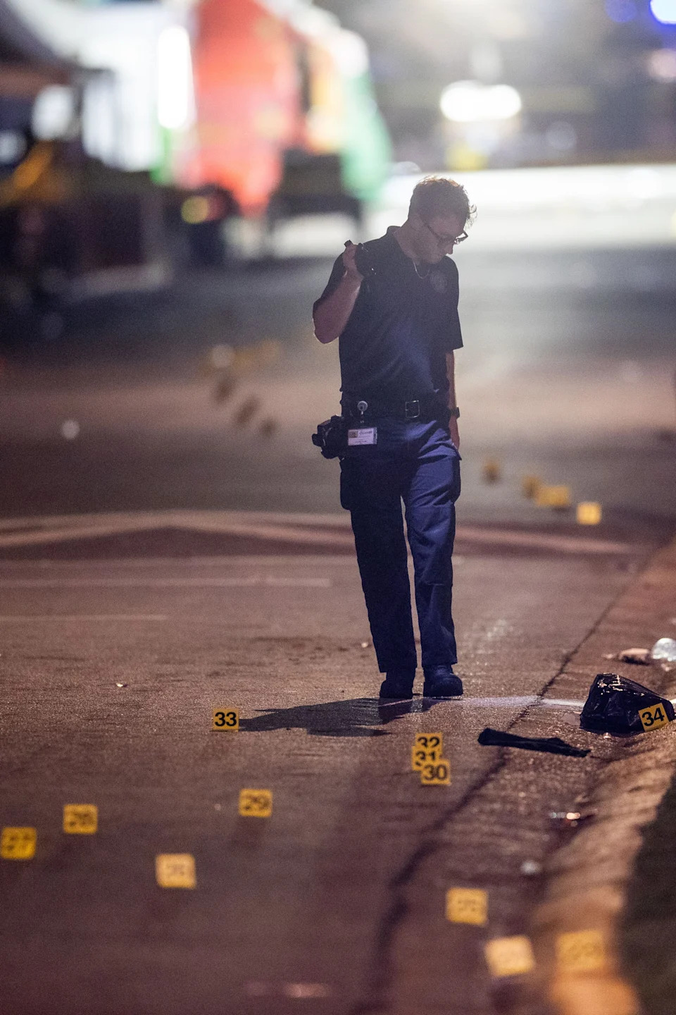 An investigator with the Tallahassee Police Department uses a flashlight to look over dozens of evidence markers that snake down Perry Street behind Florida A&M University's Bragg Memorial Stadium as the TPD investigates a mass shooting Saturday, Oct. 24, 2026.