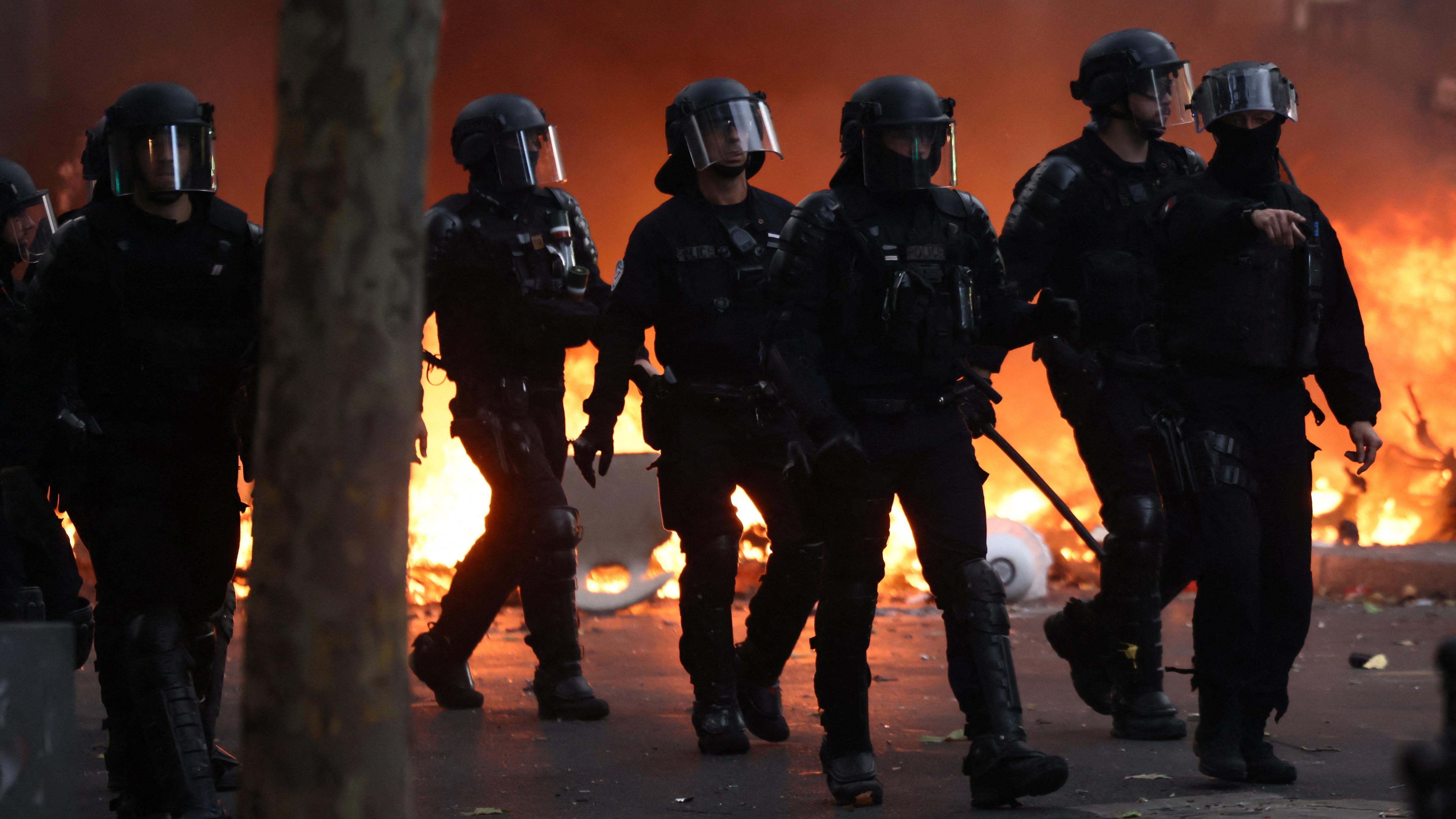 French riot police walk past a burning barricade amid clashes with protesters during a day of demonstrations 